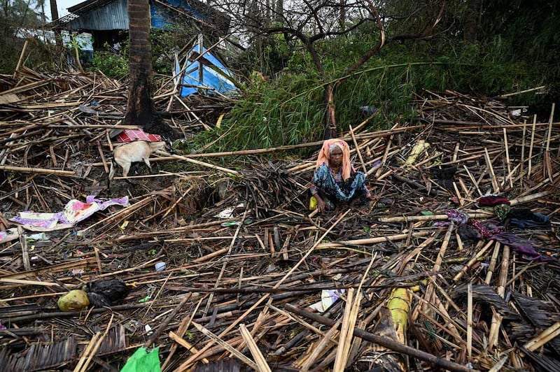 A Rohingya woman sits amid the shattered remains of her home in the Basara refugee camp in Sittwe, Myanmar, on Tuesday, May 16, 2023. Credit: AFP