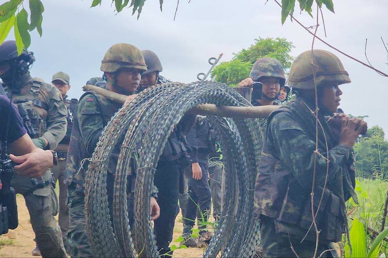 This image released by Agence Kampuchea Presse shows Thai soldiers carrying barbed wire in a disputed Thai-Cambodia border in Banteay Meanchey province, Sept. 17, 2025.