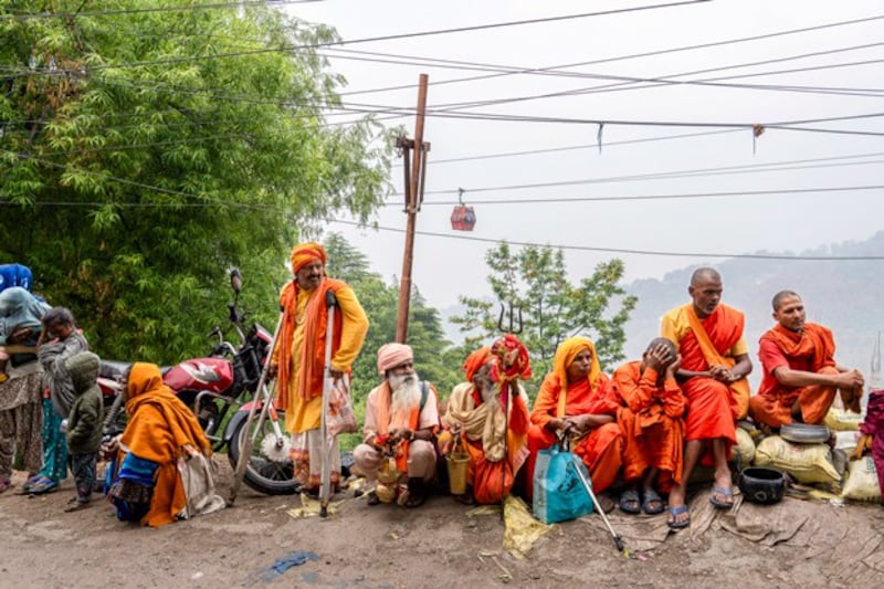 Buddhist monks and Hindu holy men sit by a roadside expecting alms as Tibetans mark the day of Buddha's birth, death and enlightenment in Dharamsala, India, May 23, 2024. (Ashwini Bhatia/AP)