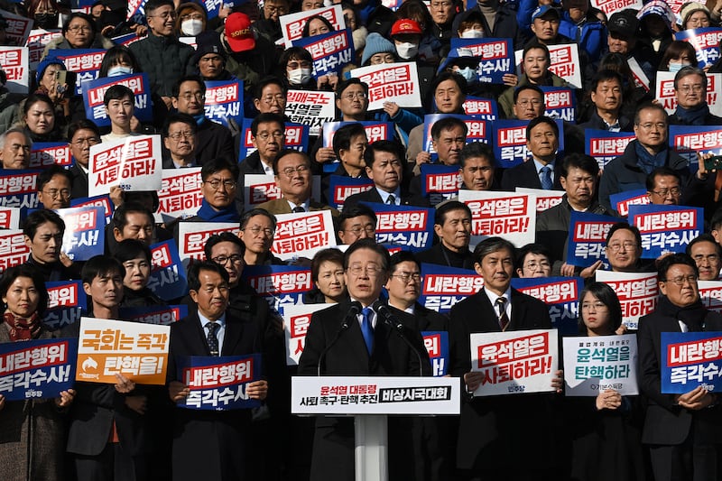 2024年12月4日，南韓國會議員及反對黨民主黨成員舉著寫著「尹錫悅應該辭職！」的標語牌（法新社圖片）