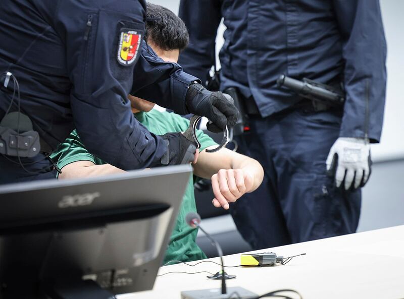 图为德国伊策霍市的法警5月24日在庭上移除杀人嫌犯易卜拉欣的手拷。易卜拉欣在德国北部持刀伤人致死,被伊策霍市法院判无期徒刑。(美联社图片))