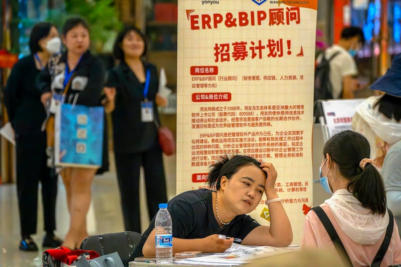 A recruiter talks with an applicant at a booth at a job fair at a shopping center, June 9, 2023 in Beijing. (Mark Schiefelbein/AP)
